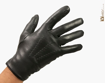 Puede incluir: Guantes de cuero negro con un patrón cosido en el dorso de la mano.