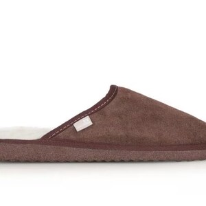 May include: Brown suede slippers with a white faux fur lining. The slippers have a closed toe and a flat sole.