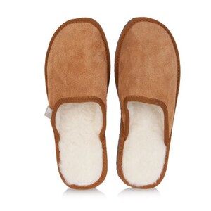 May include: A pair of brown suede slippers with a white sheepskin lining. The slippers have a closed toe and a slip-on design.