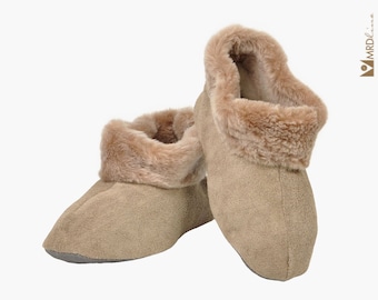 Könnte beinhalten: Ein Paar beigefarbene Slipper-Stiefeletten aus Wildleder mit einem Kunstfell-Besatz. Die Stiefeletten sind weich und gemütlich, perfekt um die Füße im Winter warm zu halten.