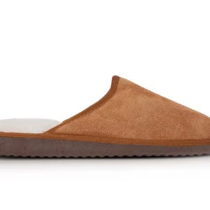 May include: A pair of brown suede slippers with a white fleece lining. The slippers have a brown rubber sole.