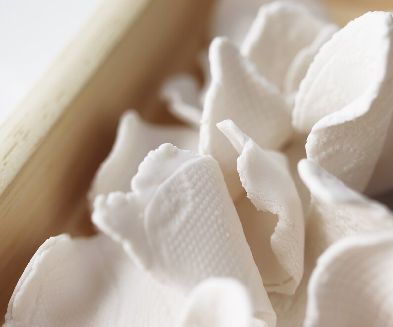May include: Close-up of white, delicate, and slightly translucent rice paper, arranged in a wooden bowl. The paper is soft and textured, with a slightly crinkled appearance.