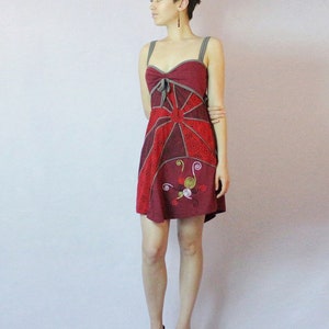 May include: A red and gray sleeveless dress with a geometric pattern and a floral design. The dress has a sweetheart neckline and a fitted bodice. The model is wearing black platform heels.