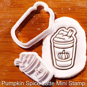 Może przedstawiać: Biały plastikowy zestaw wykrawaczy i stempli do ciasteczek w kształcie pumpkin spice latte. Zestaw zawiera prostokątny wykrawacz, stempel z wzorem latte i odbite ciastko na białej powierzchni. Tekst "Pumpkin Spice Latte Mini Stamp" znajduje się na dole.