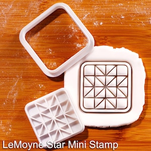 Può includere: Set di timbri LeMoyne Star Mini bianchi con cornice quadrata e motivo a stella dettagliato. Il timbro è su una superficie di legno. Il testo "LeMoyne Star Mini Stamp" è in basso nell'immagine.