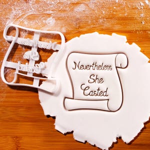 Tagliabiscotti "Strega femminista": timbro a forma di pergamena "Nonostante tutto ha lanciato il suo incantesimo"