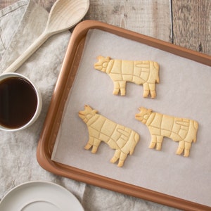 Peut inclure: Trois biscuits en forme de vache en sucre brun sur une plaque &agrave; p&acirc;tisserie recouverte de papier sulfuris&eacute;.