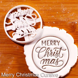 May include: A white plastic cookie cutter with the words "Merry Christmas" in a cursive font. The cutter is next to a white, circular imprint of the same text on a piece of dough. The words "Merry Christmas Cursive" are at the bottom.