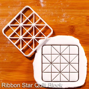 Könnte beinhalten: Ein weißer, quadratischer Ausstecher mit einem geometrischen Gittermuster aus Dreiecken und Quadraten sowie ein Stück weißer, ausgerollter Teig mit dem eingeprägten Ribbon Star Quilt Block Design, das den präzisen Abdruck des Ausstechers zeigt.