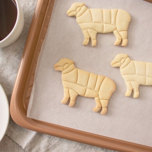 Peut inclure: Trois biscuits sabl&eacute;s en forme de mouton sur une plaque &agrave; p&acirc;tisserie recouverte de papier sulfuris&eacute;.