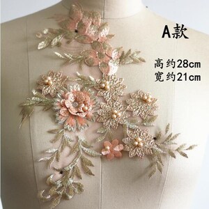 May include: A delicate floral applique with gold and peach embroidery. The applique features a variety of flowers and leaves, with pearl accents. The applique measures approximately 28 inches tall and 21 inches wide.