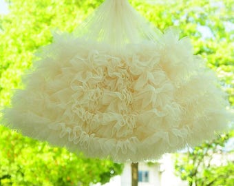 May include: A white tulle fabric with a ruffled design. The fabric is gathered and layered to create a voluminous, fluffy look.