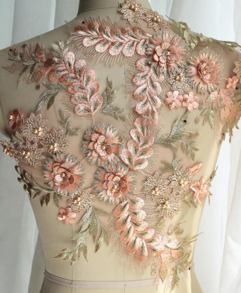 May include: Peach and gold floral applique with pearl embellishments. This delicate lace trim is perfect for adding a touch of elegance to any garment.