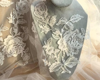 May include: White floral lace fabric with delicate embroidery and small beads. The lace features a repeating pattern of flowers and leaves.