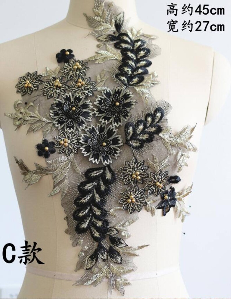 May include: Black and gold floral lace applique with beaded accents. The applique measures approximately 17.7 inches tall and 10.6 inches wide.