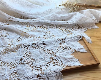 May include: White lace fabric with a delicate leaf pattern. The lace is soft and flowing, and it would be perfect for a variety of crafting projects.