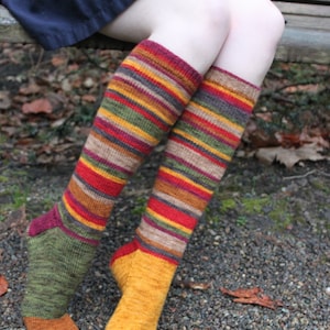 May include: A pair of striped knee-high socks in shades of brown, red, yellow, and green. The socks are made of a soft, knitted fabric and have a comfortable fit.