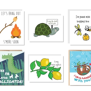 May include: Set of six greeting cards with various illustrations and puns. The cards feature a campfire with a marshmallow, a turtle, a dragonfly, a crocodile, lemons, and a sloth.