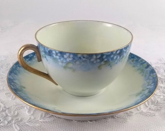 Antique cup and saucer with white daisies on a royal blue border, hand painted on the palest yellow porcelain