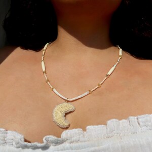 Collana con ciondolo a forma di luna, realizzata a mano con perline, dentalium, osso di bufalo e perline di cristallo.