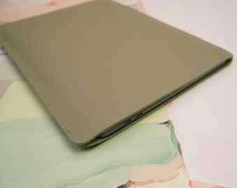 Può includere: Una custodia per laptop in pelle verde chiaro con un bordo cucito.