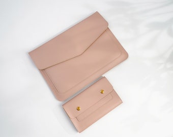 Può includere: Due pochette in pelle rosa cipria, una più grande dell'altra, con dettagli dorati. La pochette più grande ha una chiusura a lembo e la più piccola ha una chiusura a scatto.