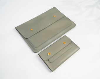 Può includere: Due pochette in pelle grigia con chiusura a bottone dorata. La pochette più grande è leggermente più grande della più piccola.