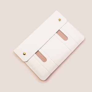May include: White leather laptop sleeve with three interior pockets and gold accents.