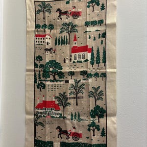 May include: A rectangular beige linen wall hanging featuring a repeating folk-art print in red, green, and black. The design depicts a rural landscape with houses, a church, horse-drawn carriages, and various trees enclosed by a black border.