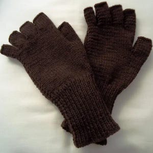 Op de afbeelding: Een paar bruine vingerloze handschoenen, gebreid met een getextureerde steek. De handschoenen hebben een geribbelde manchet en openingen voor de vingers. De kleur is een rijk, donkerbruin en de handschoenen lijken gemaakt van een zacht, warm materiaal.