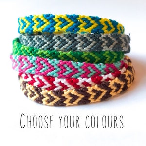May include: A stack of colourful friendship bracelets in various patterns, including yellow, blue, grey, green, pink, red, brown, and white. The bracelets are made with woven string and have a chevron pattern. The text "Choose Your Colours" is written below the bracelets.