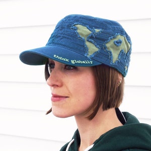 May include: A blue denim baseball cap with a green world map design and the text "think globally" embroidered on the front.