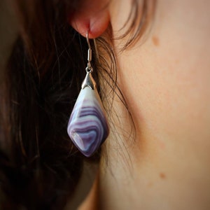 May include: A pair of silver earrings with a purple and white shell-shaped pendant.