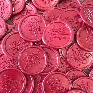 May include: A pile of red wax seals with the text "Save the Date" embossed on them.