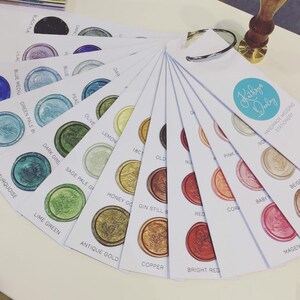 May include: A color chart of wax seal colors for wedding stationery. The chart includes a variety of colors, including turquoise, lime green, antique gold, copper, bright red, coral, baby pink, beige, and magenta. The chart also includes the text "Kithrys Duley Handmade Wedding Stationery".