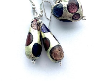Puede incluir: Un collar de cadena de plata con un colgante en forma de corazón y pendientes a juego en forma de lágrima. El colgante y los pendientes están hechos de vidrio con un acabado metálico plateado y tienen un patrón multicolor de morado, azul y marrón.