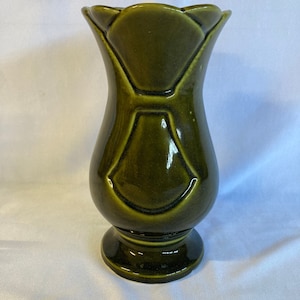 May include: A dark green ceramic vase with a scalloped rim and a geometric design. The vase has a bulbous body and a flared base.