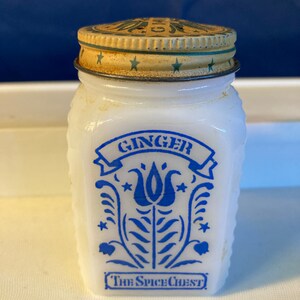 May include: White ceramic spice jar with a blue and white floral design. The jar has a metal lid with a green and gold design and says "Ginger" and "The Spice Chest" on the front.