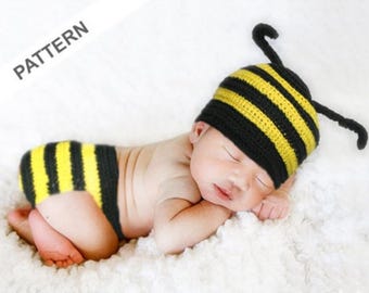 May include: A sleeping baby wearing a yellow and black striped bee costume with a hat and diaper. The costume has antennae.