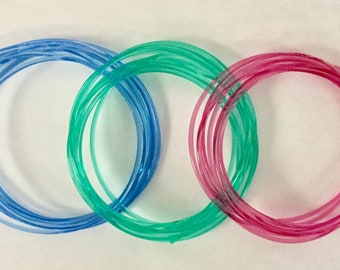 Könnte beinhalten: Drei Spulen mit durchsichtigem Kunststoffband in Blau, Grün und Rosa.