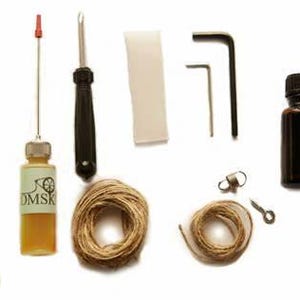 K&ouml;nnte beinhalten: Ein Satz Werkzeuge f&uuml;r Saiteninstrumente, bestehend aus einer &Ouml;lflasche, einem Schraubendreher, zwei Inbusschl&uuml;sseln, einem Filzst&uuml;ck, zwei Spulen mit Saiten, einem kleinen Metallhaken und einem Reinigungstuch.
