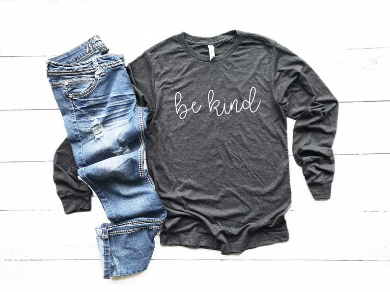 May include: A dark grey long-sleeved t-shirt with the text "be kind" in white script lettering.