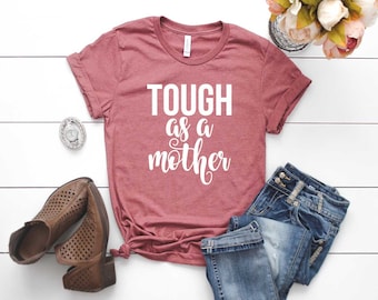 May include: A maroon t-shirt with the text "TOUGH as a mother" in white lettering.