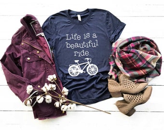 May include: A navy blue t-shirt with a white graphic of a bicycle and the text "Life is a beautiful ride."