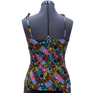 May include: A sleeveless top with a black background and a colorful floral pattern. The straps are tied at the shoulders.