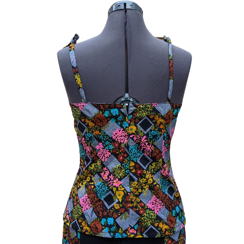 May include: A sleeveless top with a black background and a colorful floral pattern. The straps are tied at the shoulders.