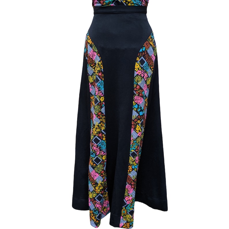 May include: A black maxi skirt with a floral print along the sides. The print features pink, yellow, blue, and green flowers.