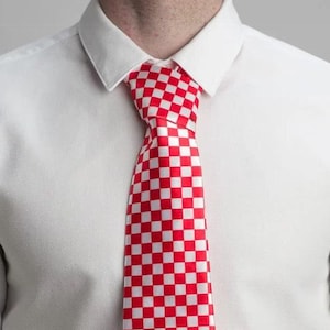 May include: A red and white checkered tie. The tie is made of a satin-like material and has a classic checkered pattern.