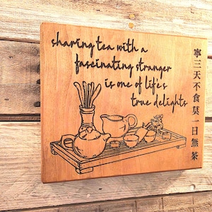 May include: Wooden plaque with engraved tea set illustration and the quote "sharing tea with a fascinating stranger is one of life's true delights." Includes Chinese characters. The plaque is brown.