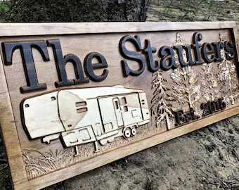 May include: A wooden sign with the text "The Staufers Est. 2016" carved into it. The sign also features a carved image of a camper and pine trees.
